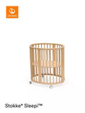Stokke mini oval crib with natural finish, adjustable height, and wheels (British brand)