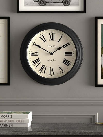 الساعة التالية ساعة حائط كلاسيكية بشريط أسود من Jones Clocks بأرقام رومانية، 40 سم - اشترِ عبر الإنترنت من McGrocer