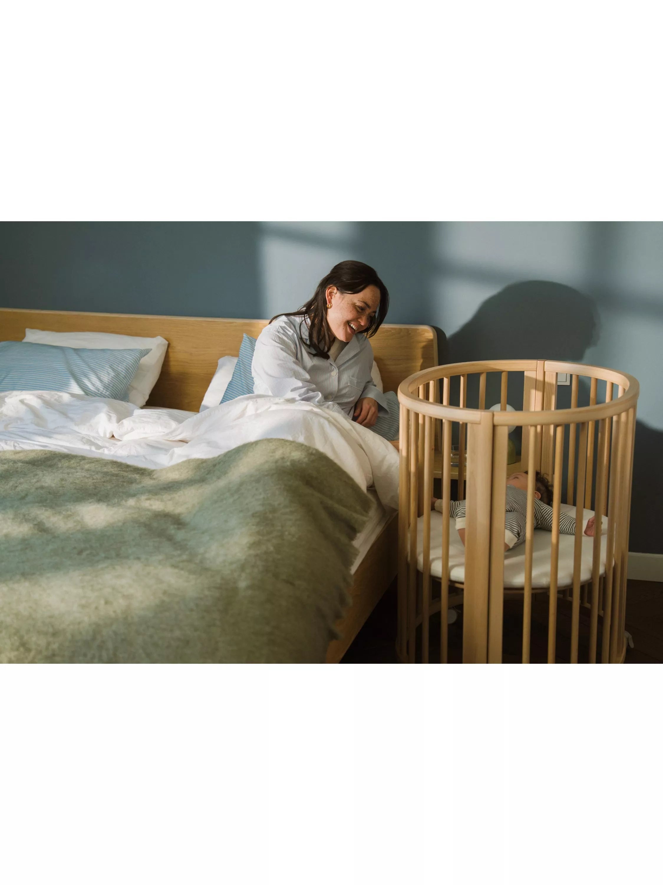 Stokke mini oval crib with natural finish, adjustable height, and wheels (British brand)