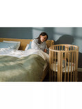 Stokke mini oval crib with natural finish, adjustable height, and wheels (British brand)