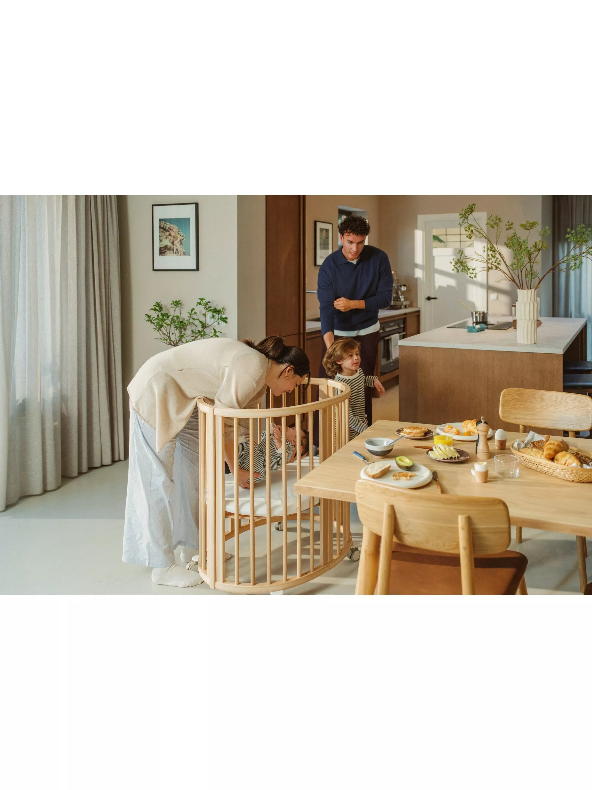 Stokke mini oval crib with natural finish, adjustable height, and wheels (British brand)