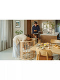 Stokke mini oval crib with natural finish, adjustable height, and wheels (British brand)