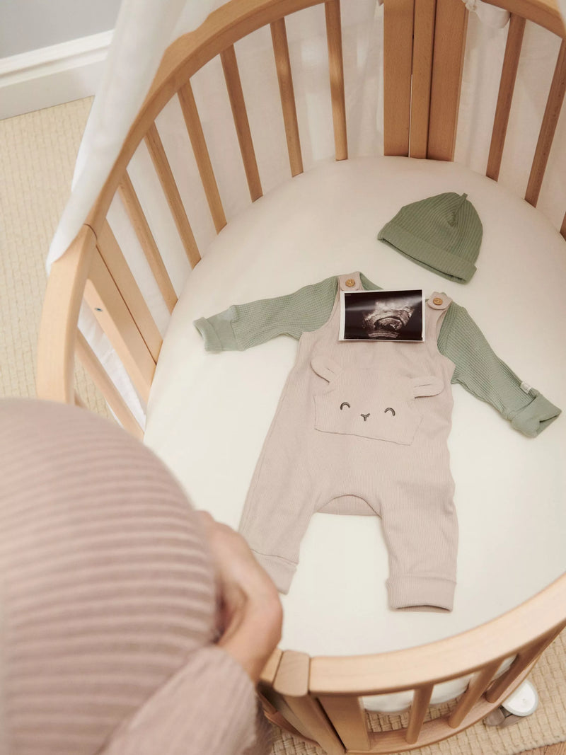 Stokke mini oval crib with natural finish, adjustable height, and wheels (British brand)