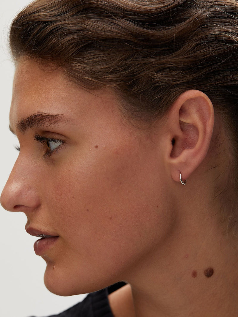 Oliver Bonas silver tone juniper mini huggie earrings, imported from the UK