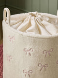 Cream bow laundry hamper with embroidered bows, imported from the UK