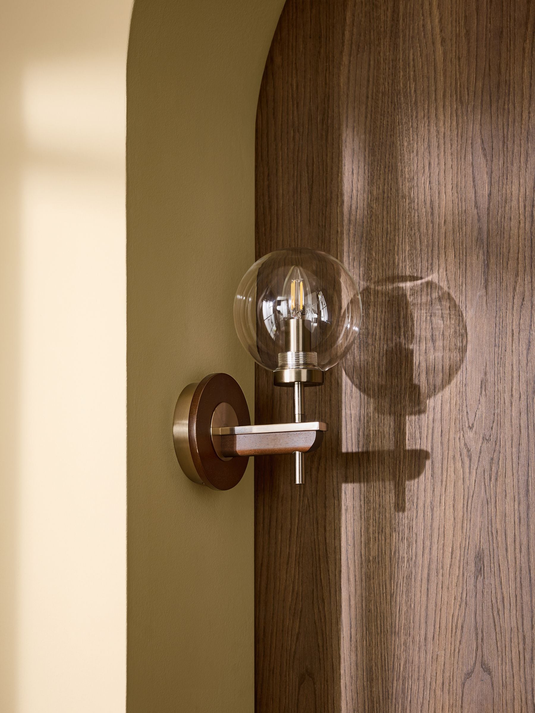 Archer wall light in dark natural wood with brass accents, British product