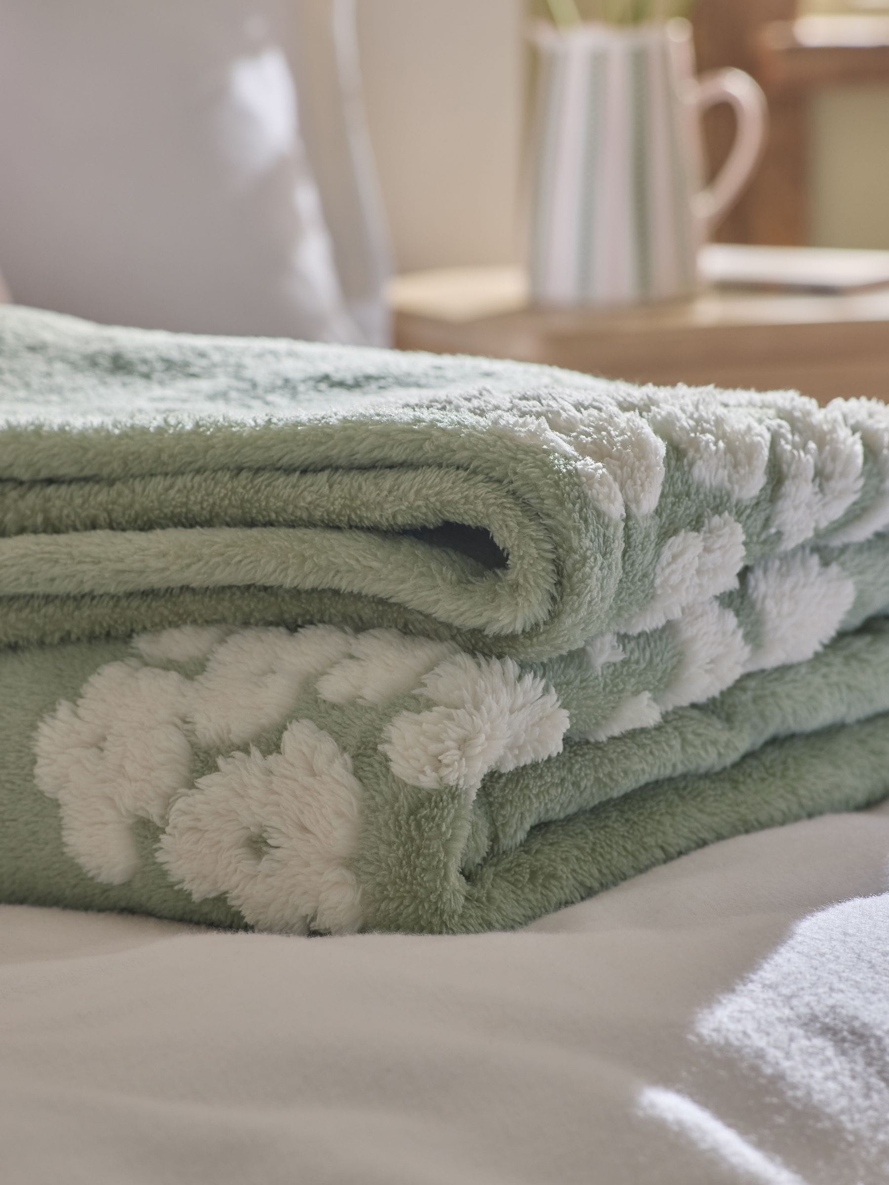 Sage green fleece throw with floral heart motifs, UK version