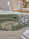 Sage green fleece throw with floral heart motifs, UK version