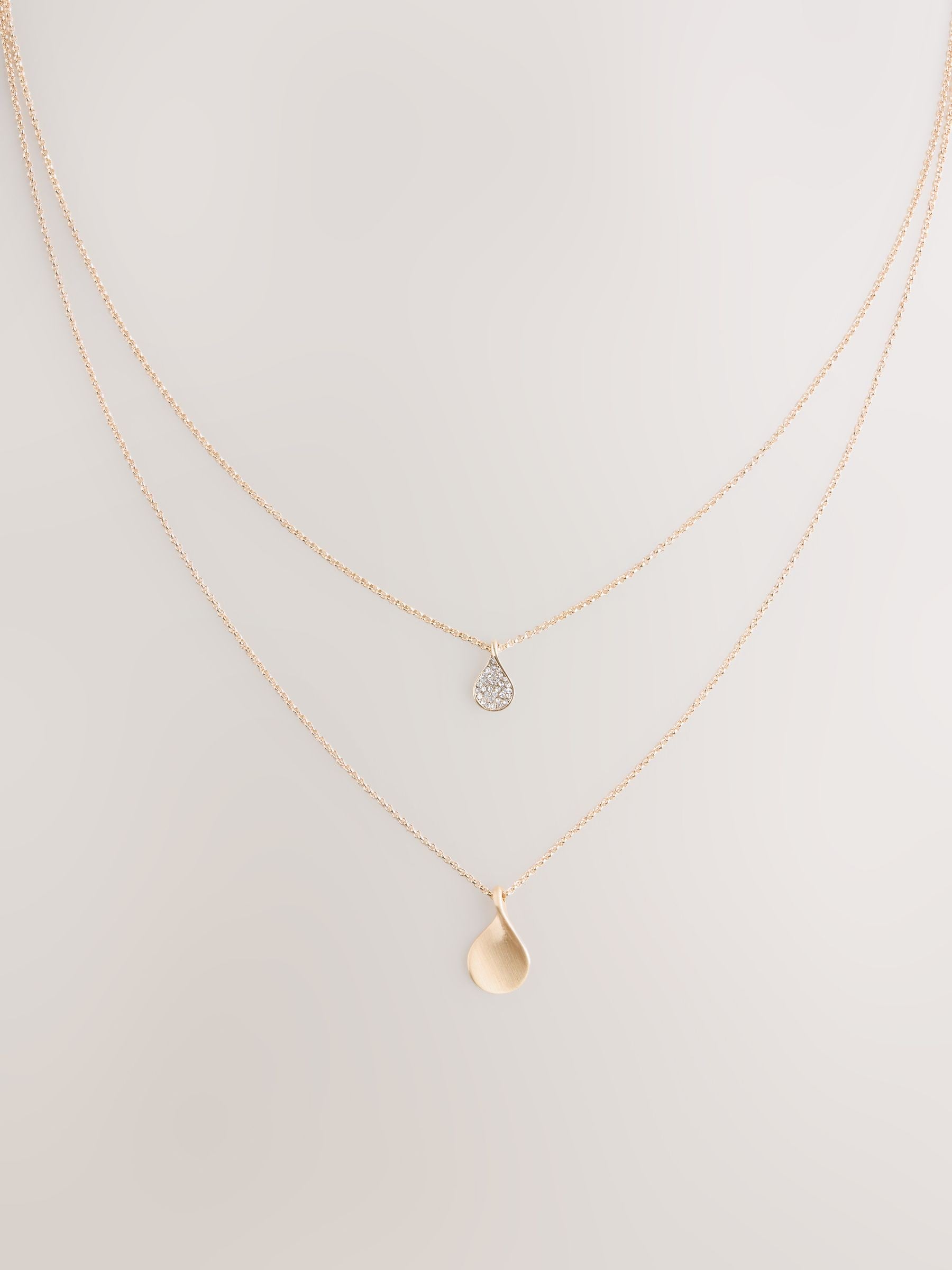 Gold tone layered necklace with sparkling and plain pendants, imported from the UK