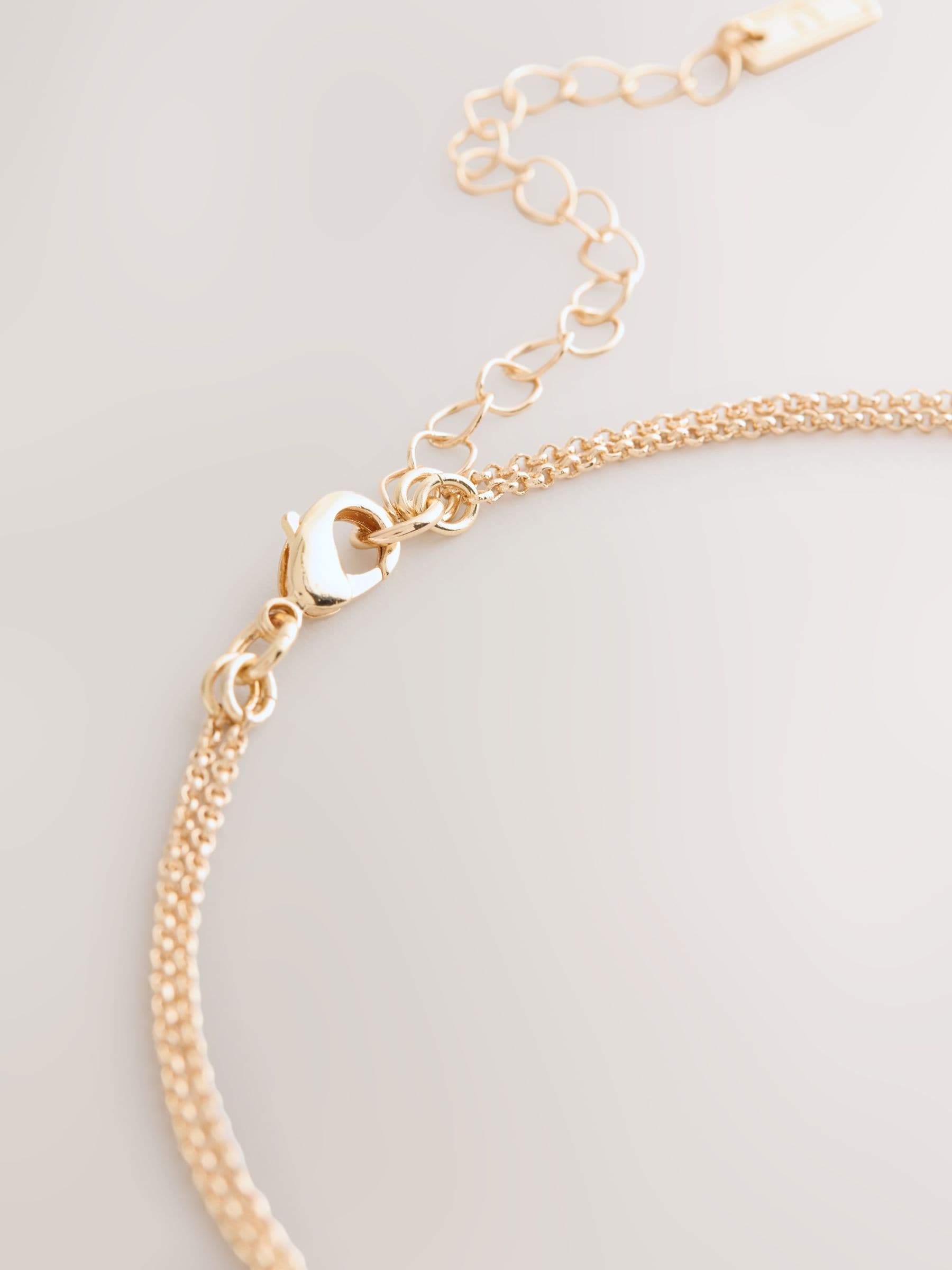 Gold tone layered necklace with sparkling and plain pendants, imported from the UK